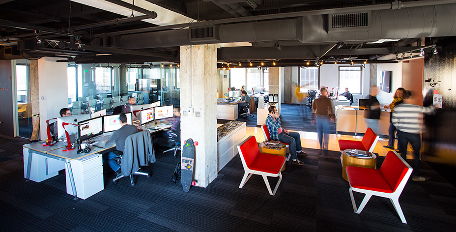 The STAPLEGUN office on the 20th floor of City Place Tower — concrete columns, red chairs, designers at work